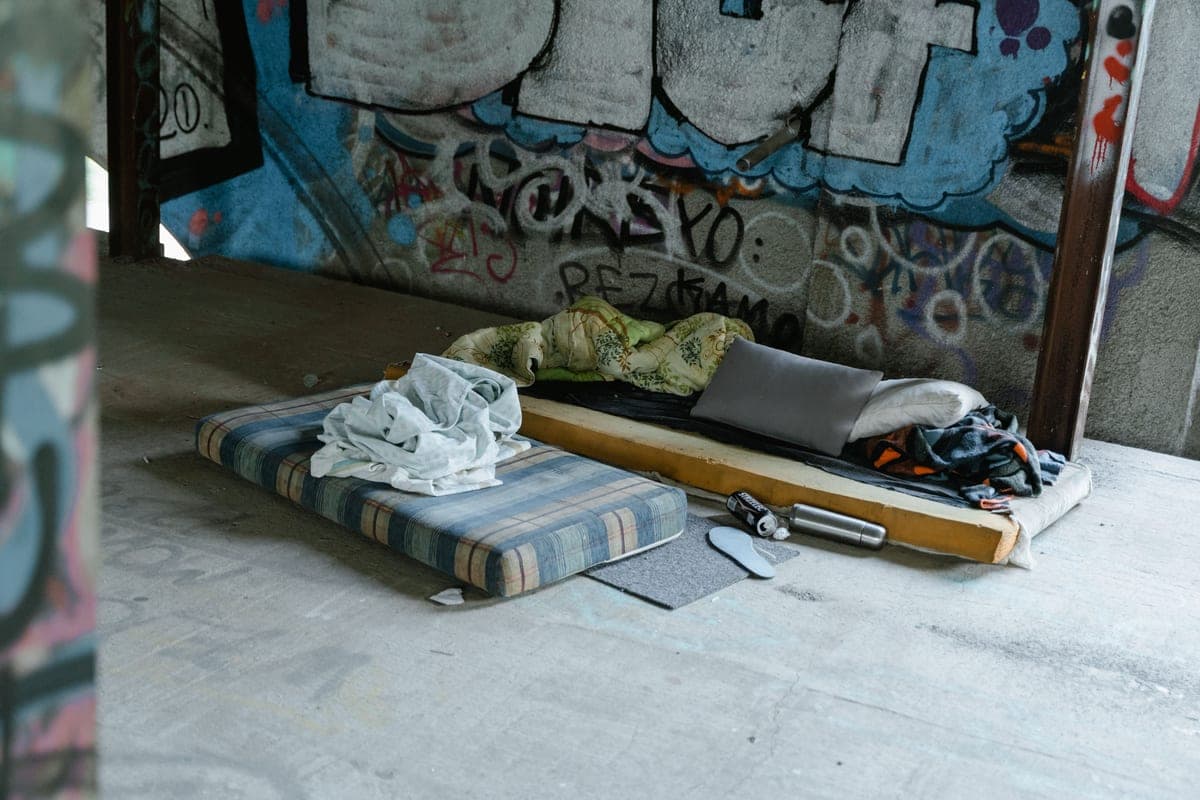 A folded foam mattress standing upright against a wall on a bare floor