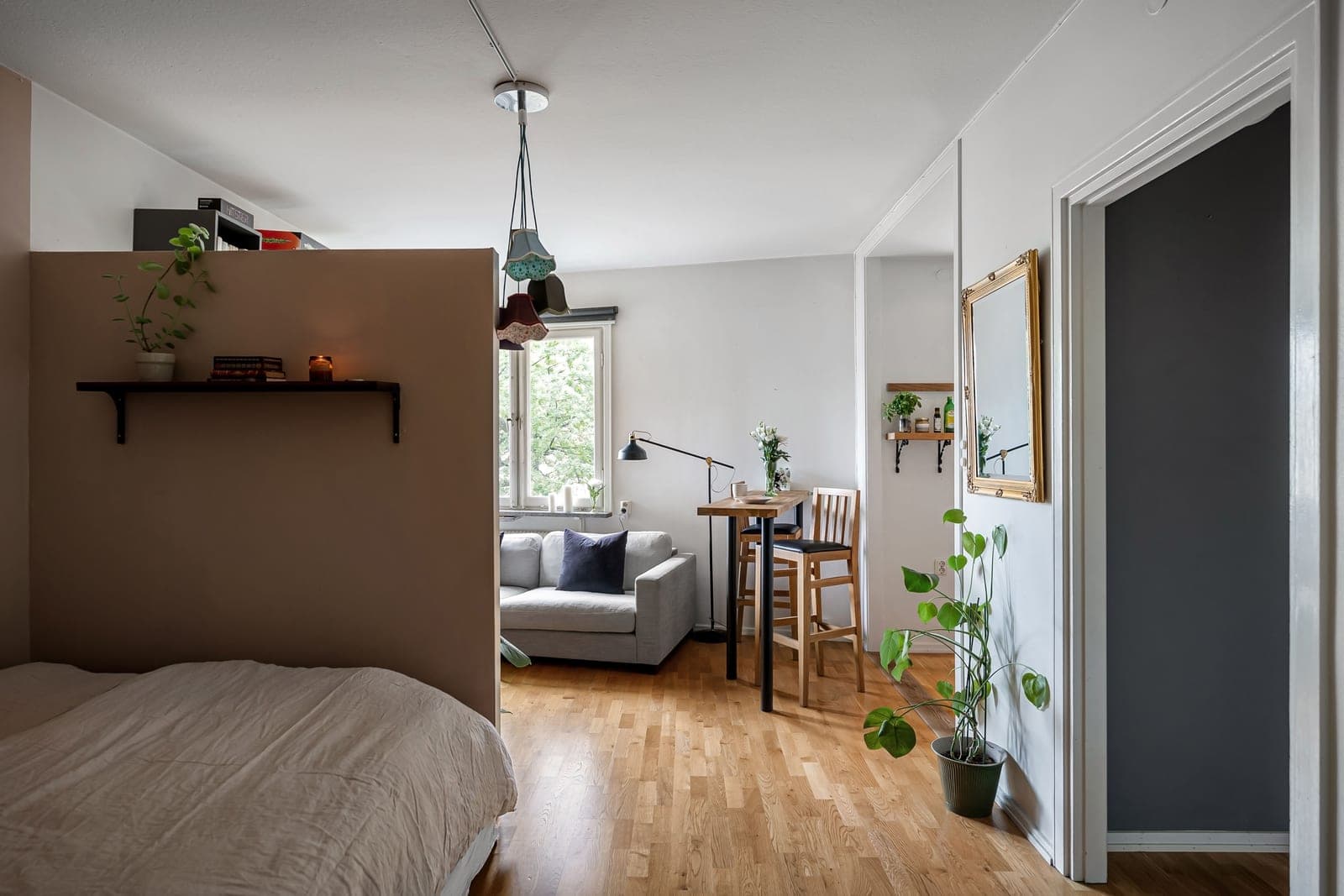 A small studio apartment living room with a sofa against the wall and limited clear floor in front of it