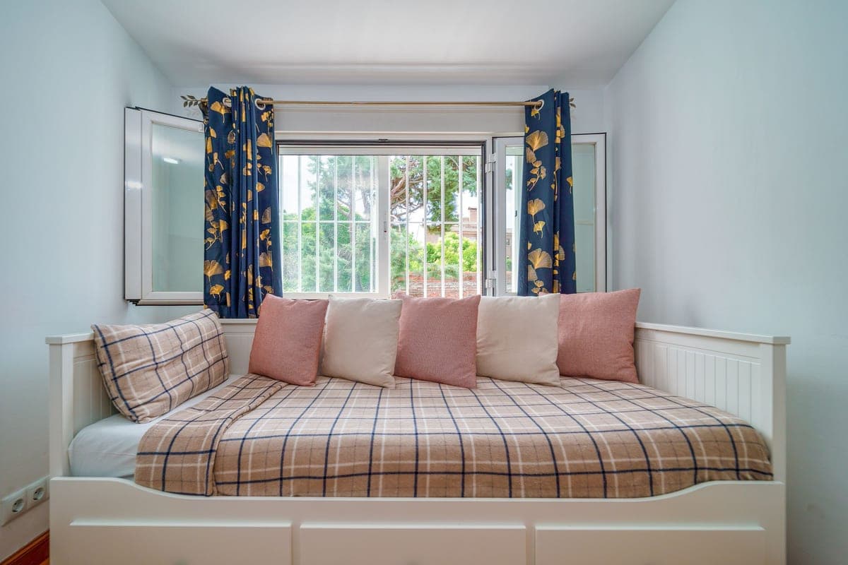 A minimal bedroom with a low daybed and cushions arranged against the wall
