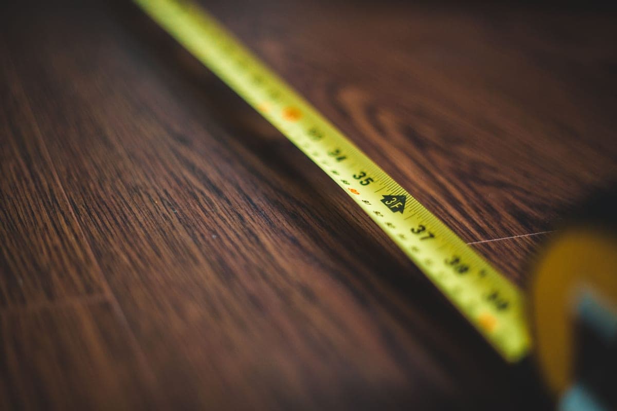 A retractable tape measure lying on a wooden floor
